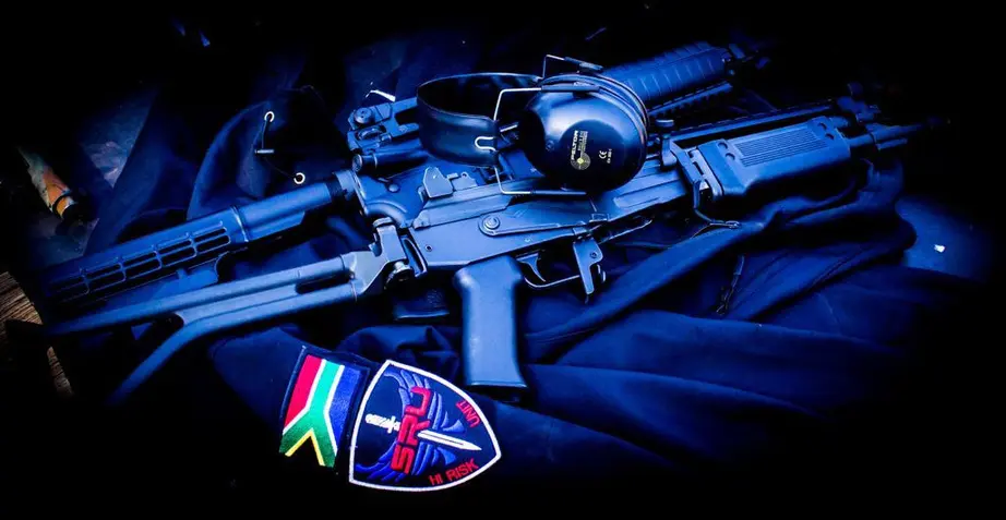 An SRU Hi-Risk Unit patch beside a rifle, lit in blue